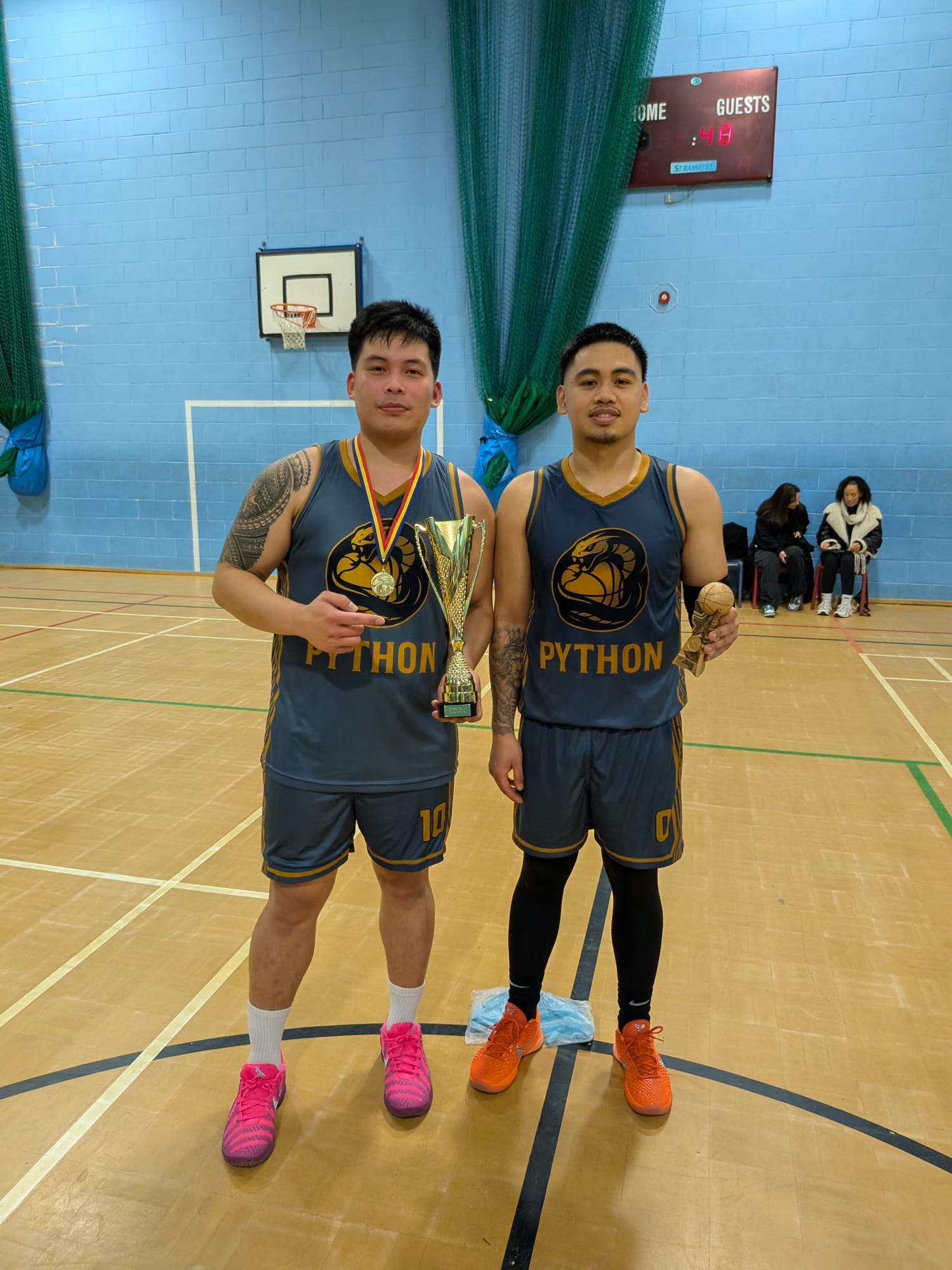 Two Team Python players posing with the championship trophy and MVP award